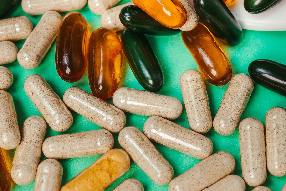 Vitamin capsules and softgel supplements spread across a table