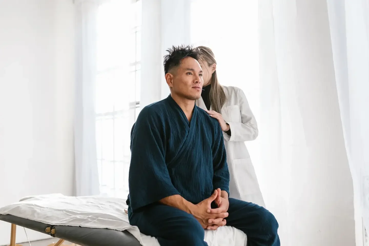 A doctor with a patient seated on a treatment bed